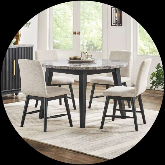 Dining table and chairs set. The table has a gray top and black legs. The chairs are upholstered in a light fabric.
