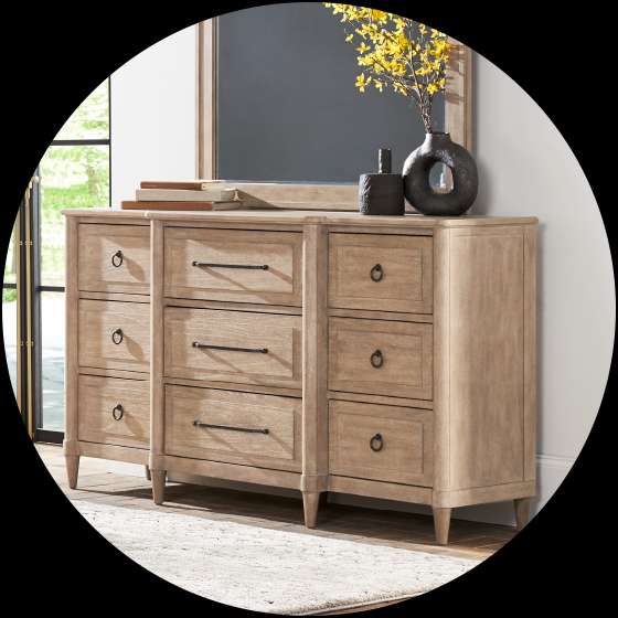 Wooden dresser with a mirror, vases, and a rug.
