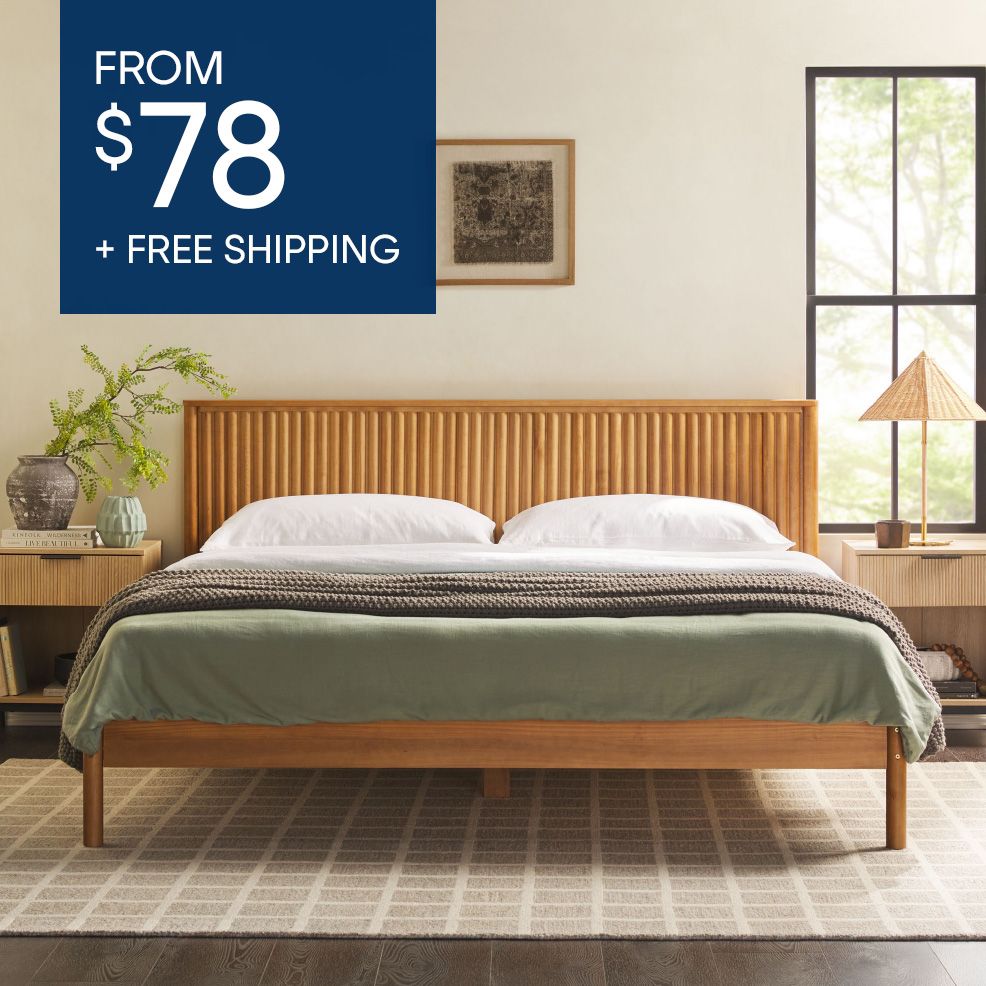 FROM $78 + FREE SHIPPING. A wooden bed frame with a headboard, green bedding, and a rug.
