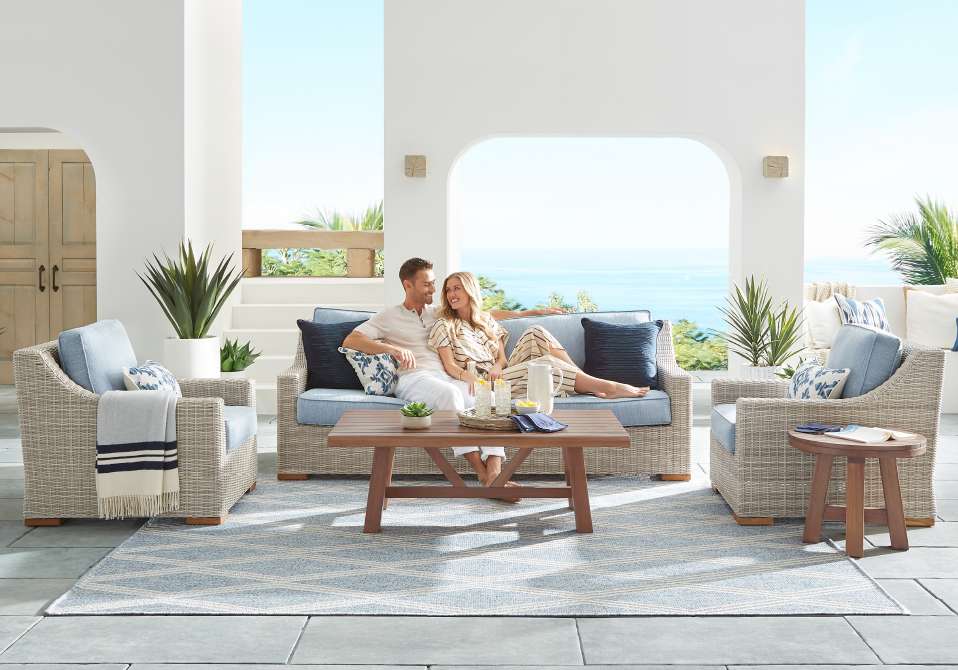 A couple relaxing on outdoor furniture with ocean view.
