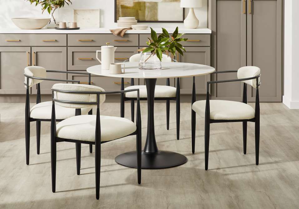 A round dining table with four chairs in a modern kitchen.
