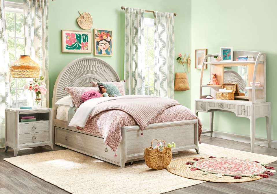 Bedroom with a bed, desk, and rug. The room is decorated in a light, airy style.
