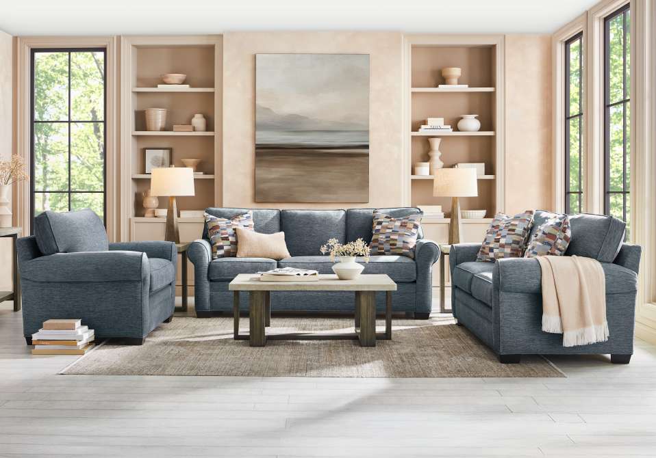 Living room with blue sofa, loveseat, and armchair, with a coffee table and rug.
