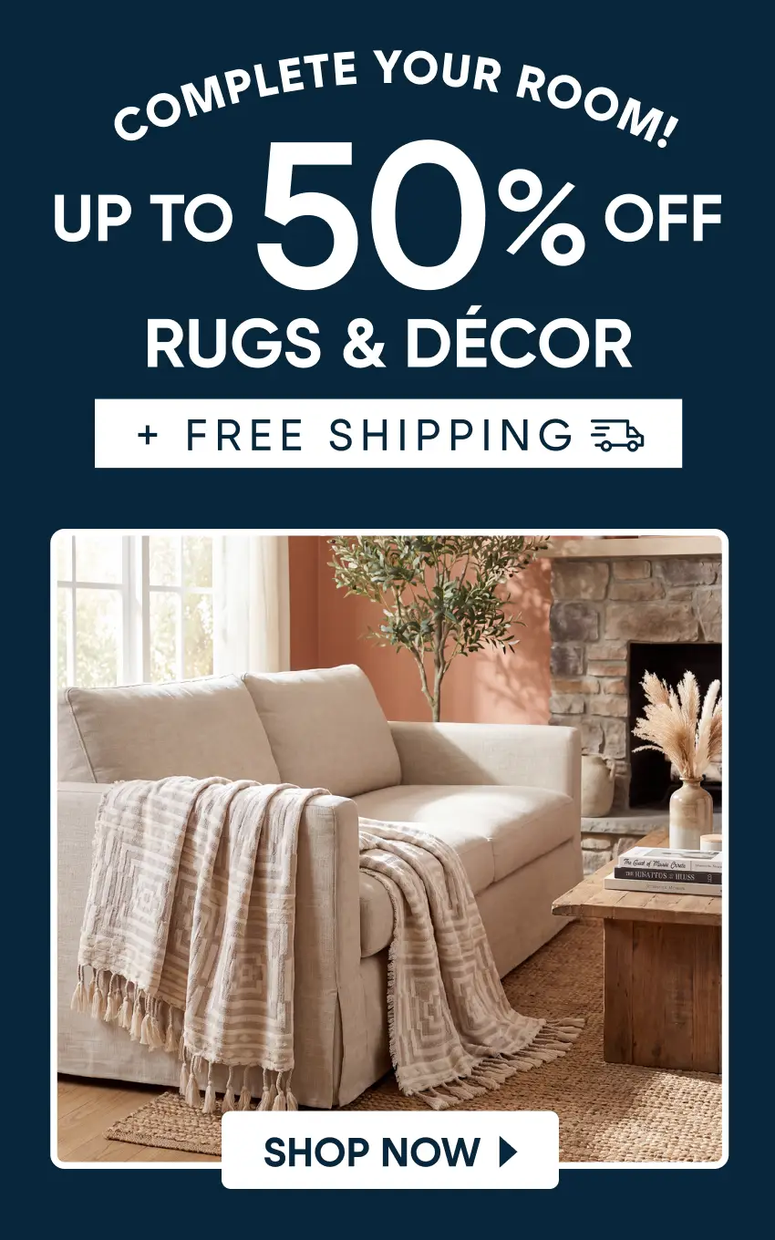 Complete your room! Up to 50% off rugs & décor + free shipping. A beige sofa with a patterned throw blanket in a living room.