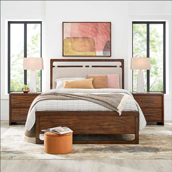 A bedroom with a bed, nightstands, lamps, and a rug.
