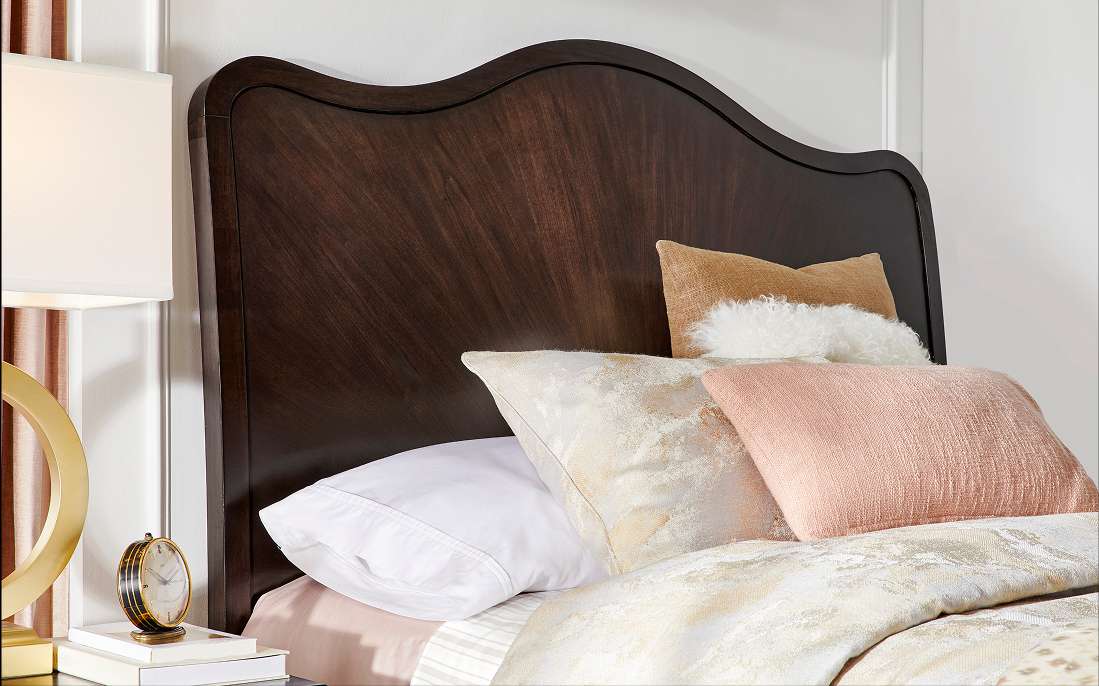 Dark wood headboard with pillows and bedding.
