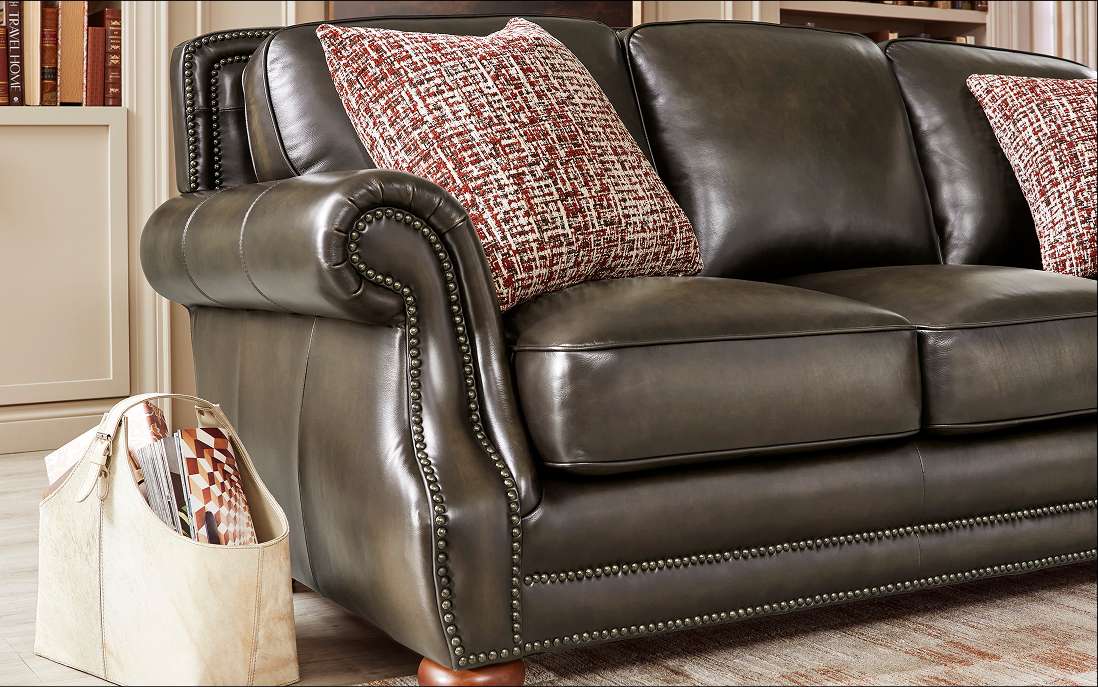 Dark brown leather sofa with two patterned pillows.
