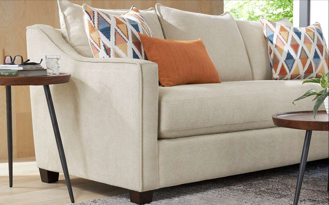 Beige sofa with patterned pillows and side tables.
