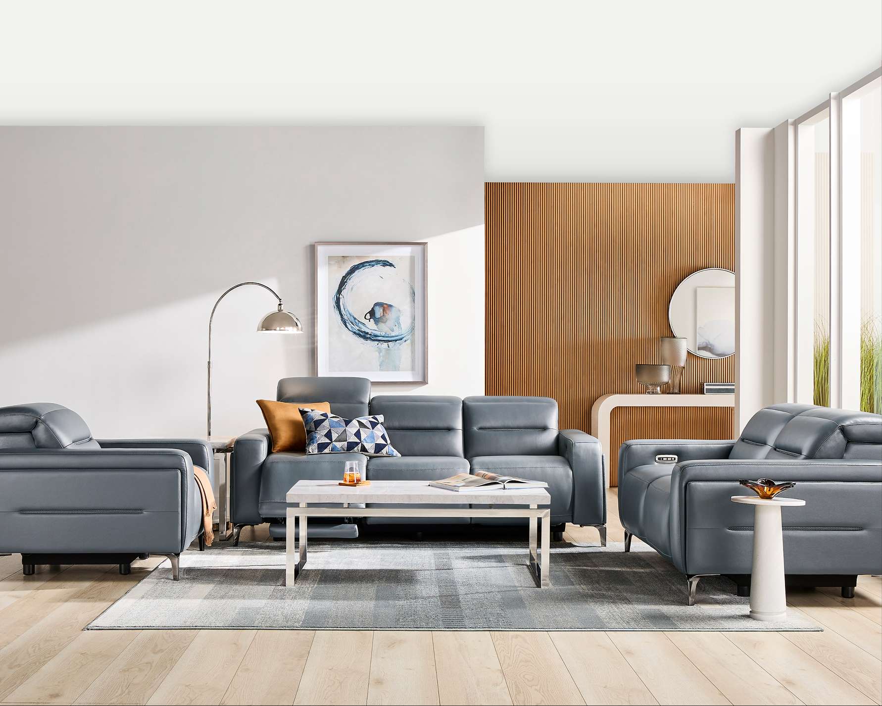 A modern living room with gray leather furniture, a rug, and a coffee table.

