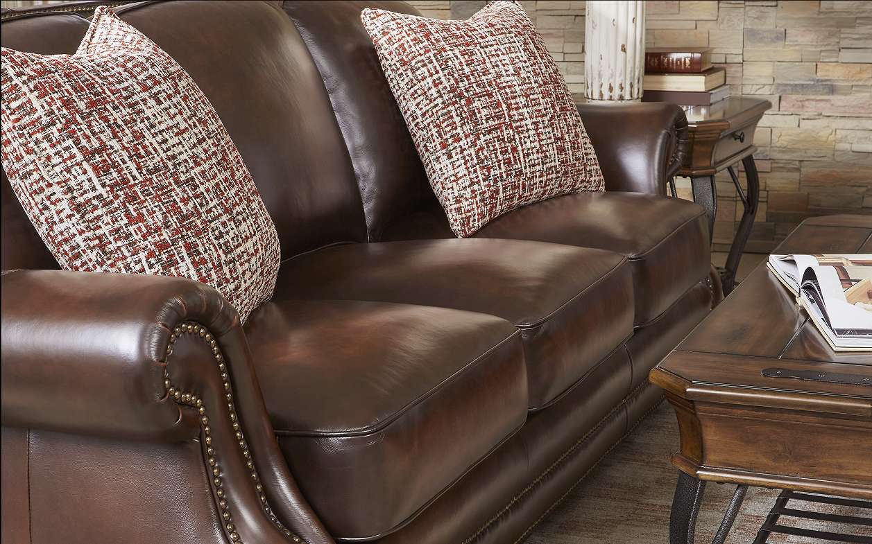 Brown leather sofa with patterned pillows.
