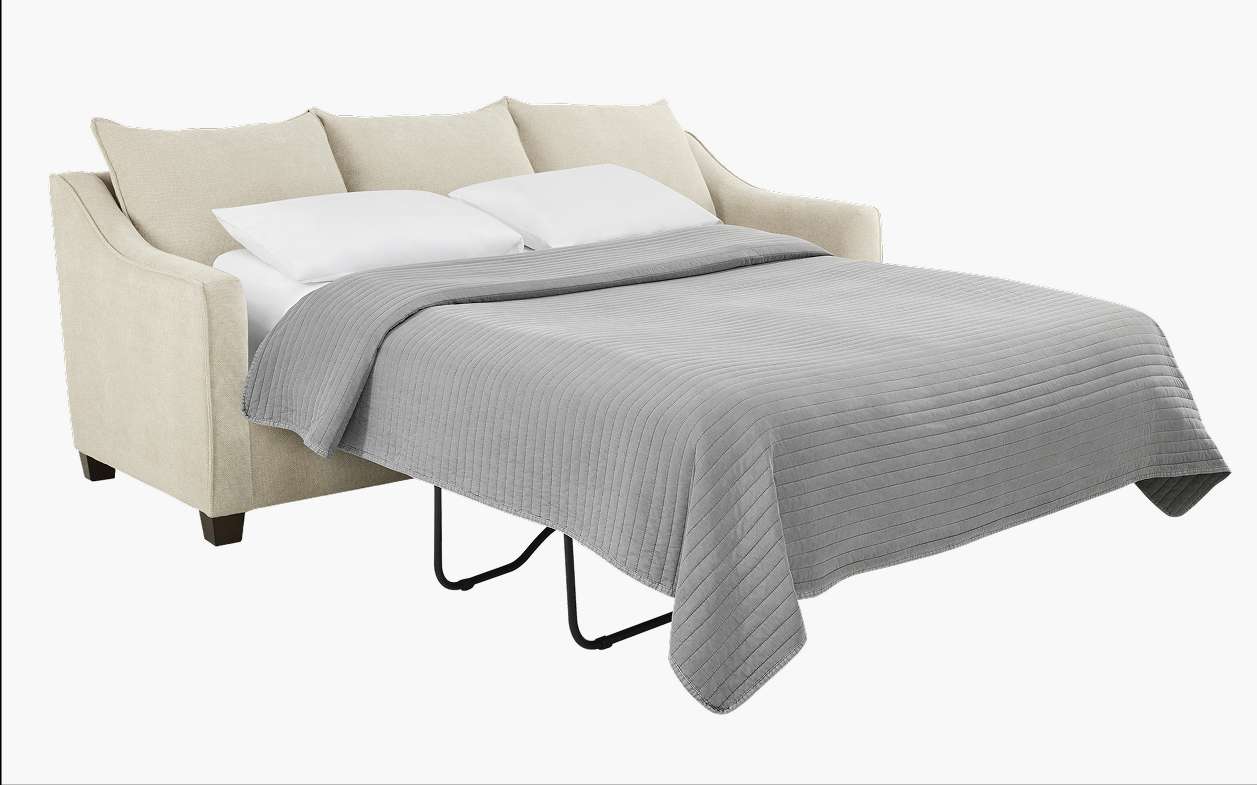 Beige sofa bed with a gray quilt.
