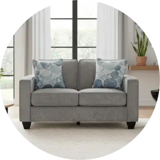 Gray loveseat with two blue patterned pillows.
