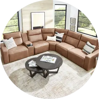 Brown leather sectional sofa with a coffee table on a patterned rug.
