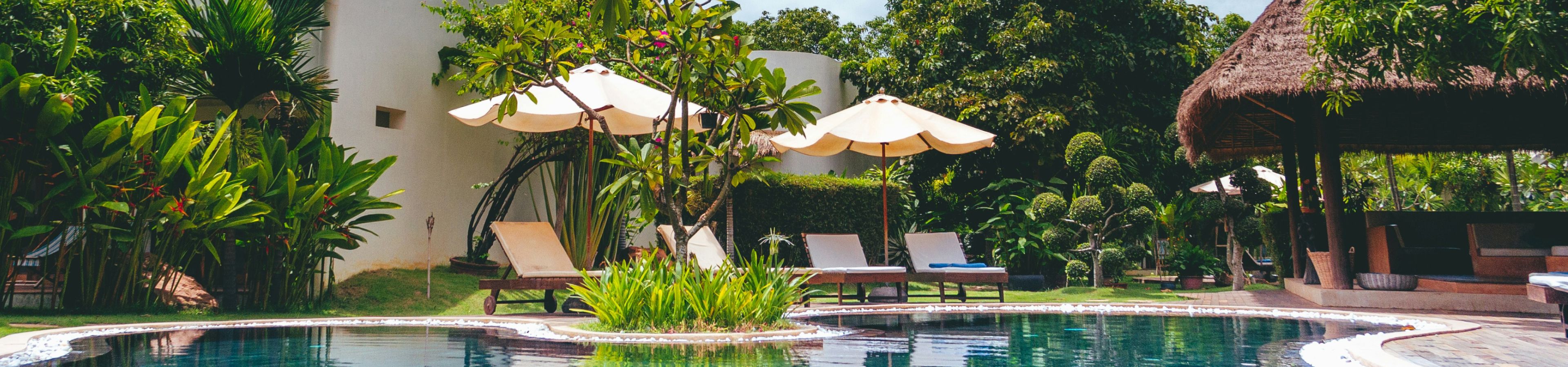 two yellow umbrellas next to a chaise lounger near the pool