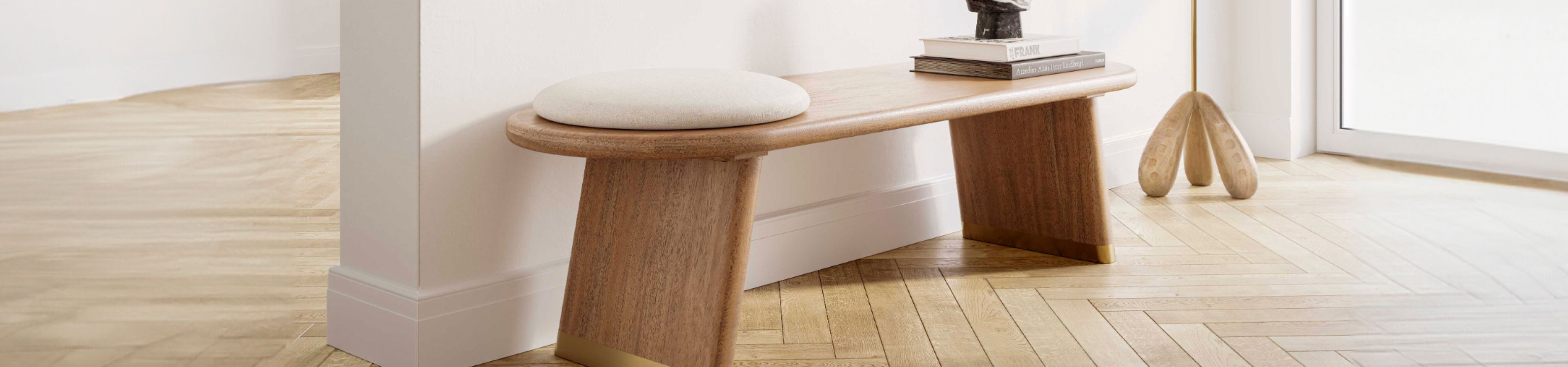 Wooden bench with a round cushion, books, and a decorative object.
