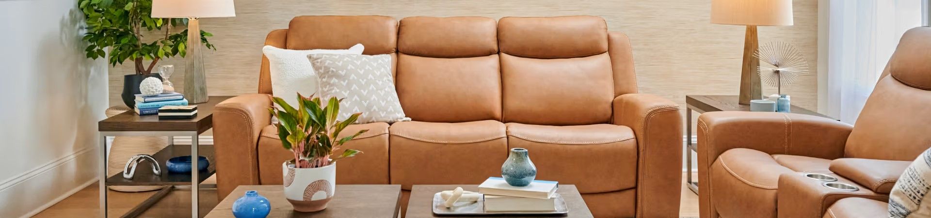 Brown leather sofa with two recliners, two side tables, and decorative items.