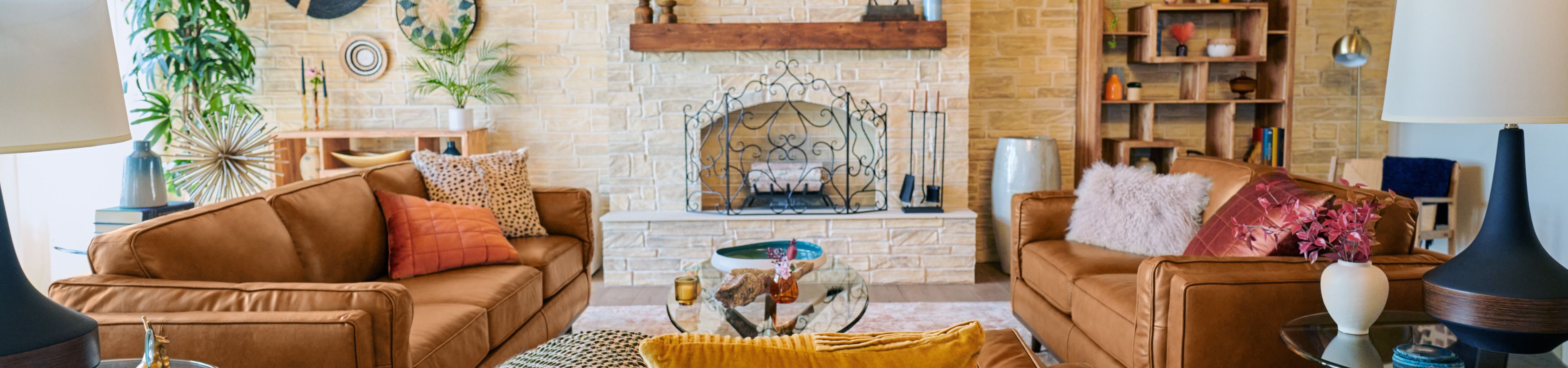 A living room with two brown leather sofas, a fireplace, and a wooden bookshelf.