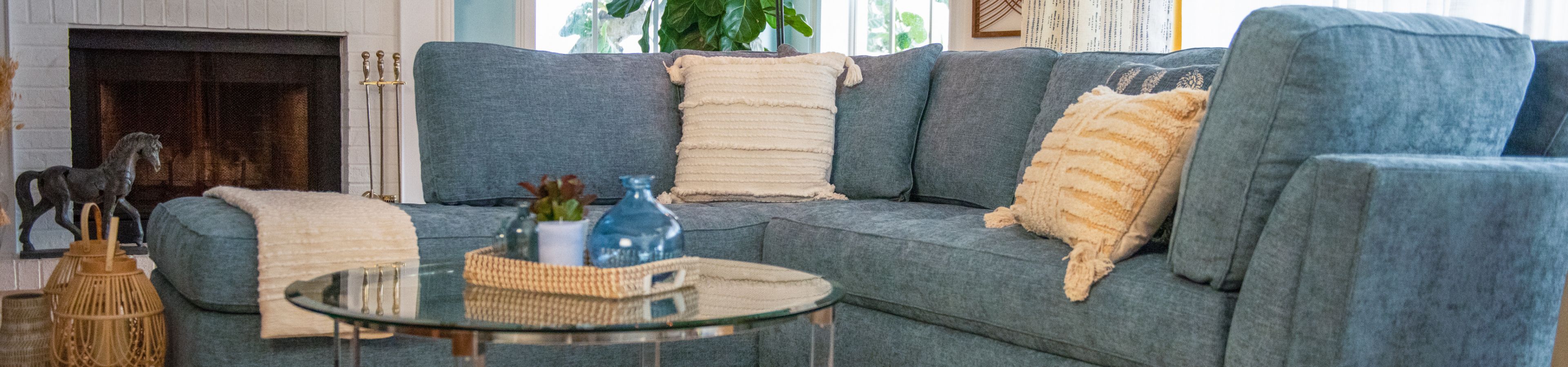 Blue sectional sofa with decorative pillows and a glass coffee table.
