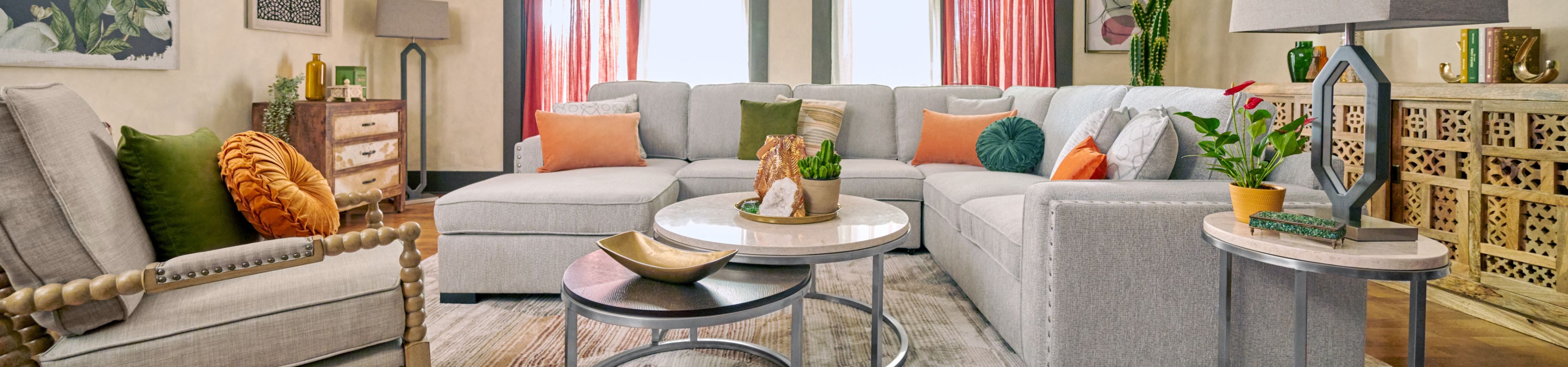 A living room with a gray sectional sofa, accent pillows, and a round coffee table.
