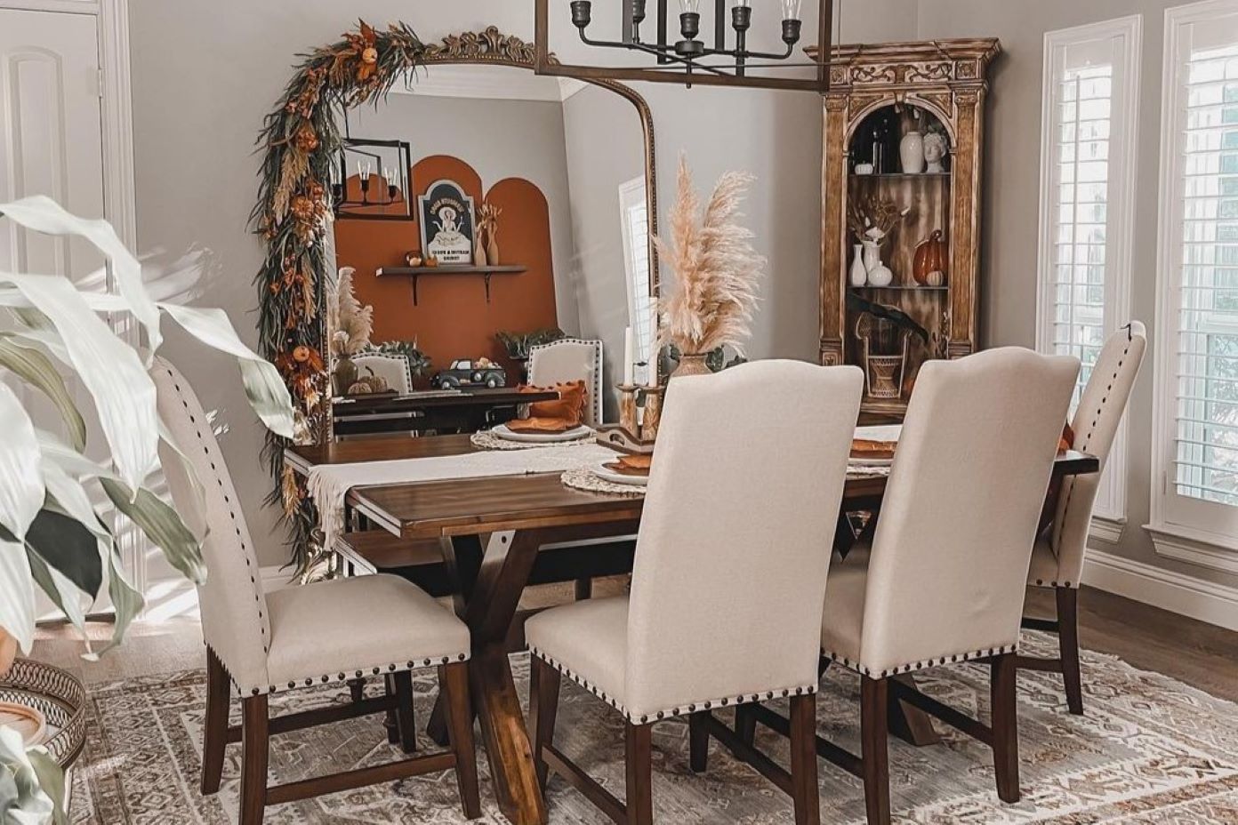Dining room with a wooden table, upholstered chairs, and a decorative mirror.
