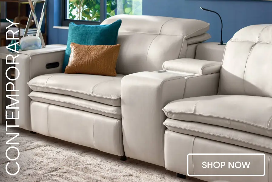 CONTEMPORARY SHOP NOW. A modern, light-colored leather reclining sofa with a teal and brown accent pillow.