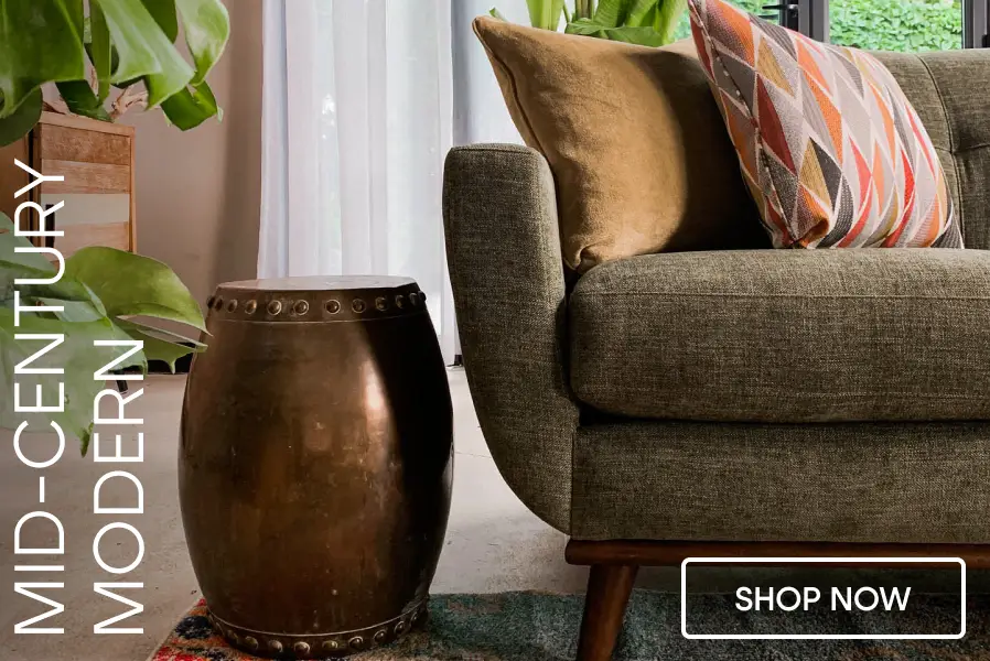 MID-CENTURY MODERN. A green sofa with patterned and solid pillows next to a metallic drum side table. SHOP NOW.