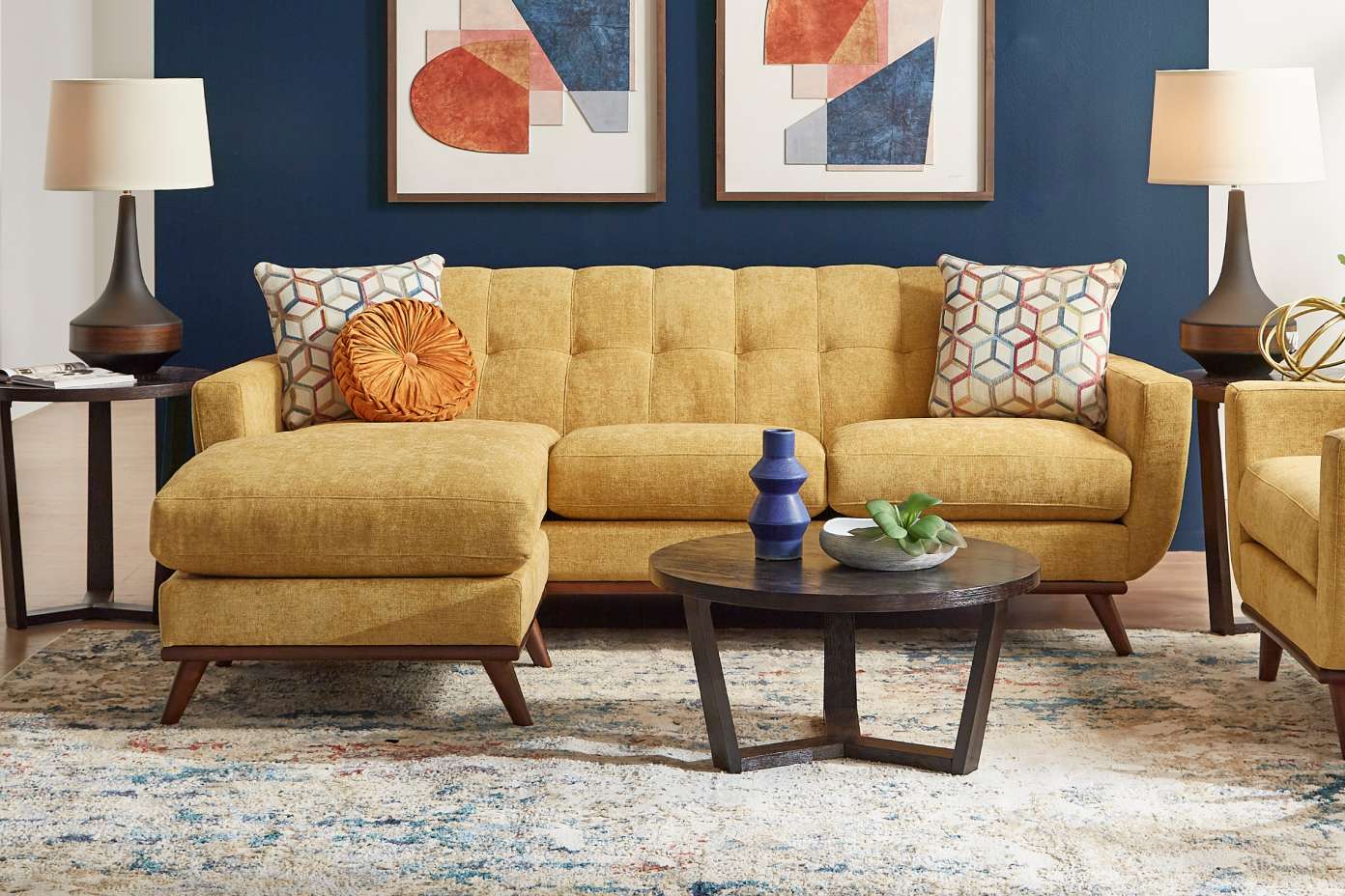 Yellow sectional sofa with a round coffee table and a patterned rug.

