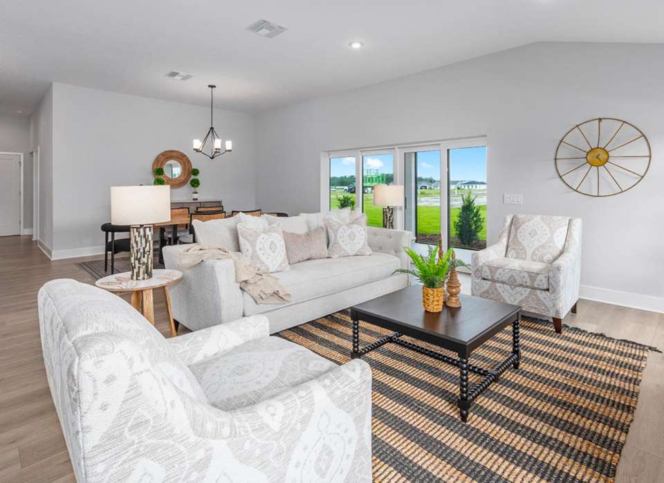 Living room with light-colored furniture, a striped rug, and a view of the outdoors.
