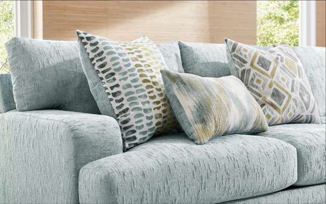 A light blue sectional sofa with patterned throw pillows.

