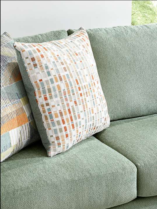 Close-up of a green sofa with two decorative pillows.
