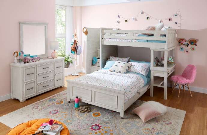 A bedroom with a bunk bed, dresser, and pink chair.
