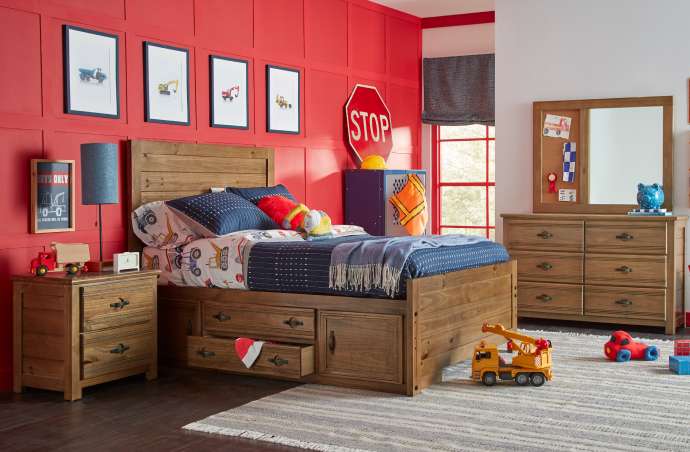 A bedroom with a construction theme, featuring a bed, dresser, and toy trucks.
