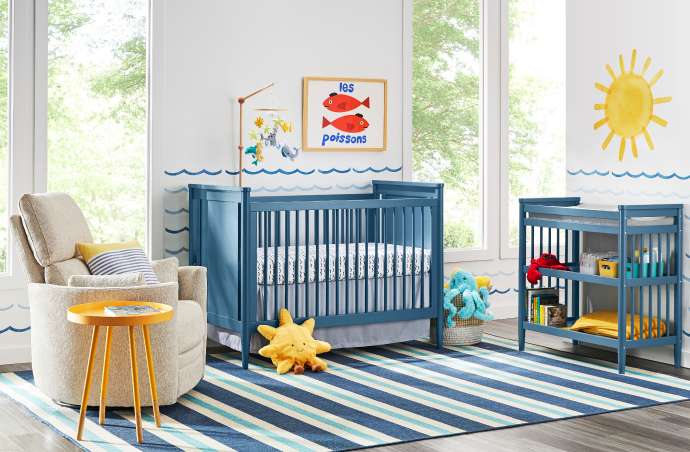 A nursery with a blue crib, changing table, and a striped rug.
