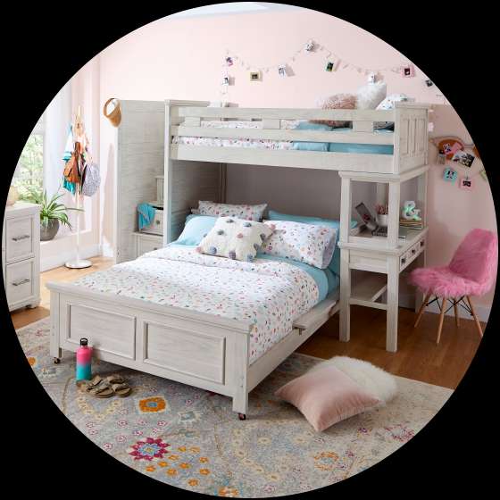 A bedroom with a white bunk bed, desk, and pink chair.
