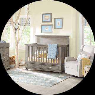 Gray crib in a nursery with a rocking chair and rug.
