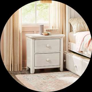 White nightstand with two drawers, next to a bed.

