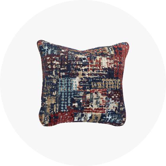 A decorative pillow with a textured, abstract pattern in shades of blue, red, and beige.
