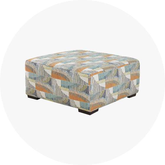 An upholstered square ottoman with a geometric pattern.
