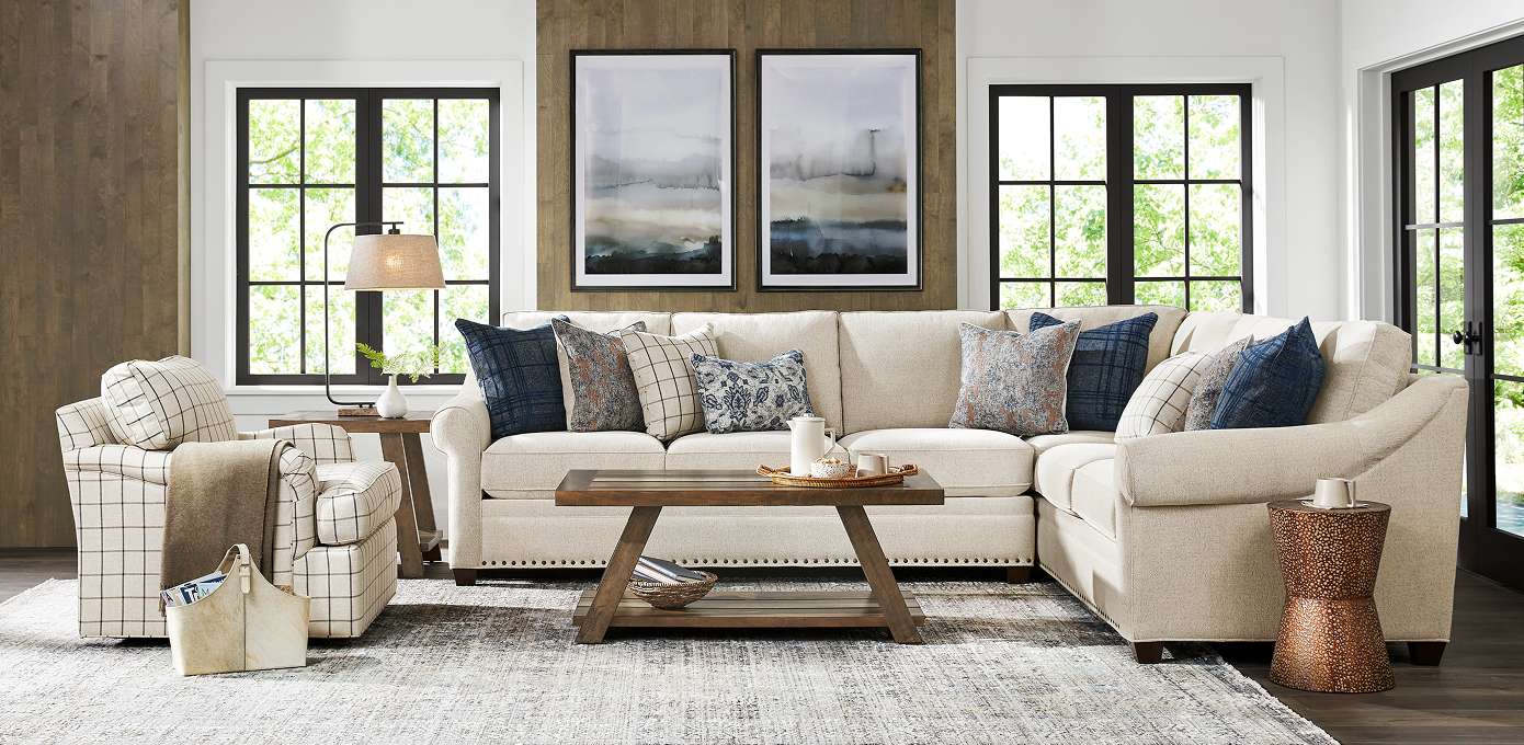 Beige sectional sofa with patterned pillows and a wooden coffee table.
