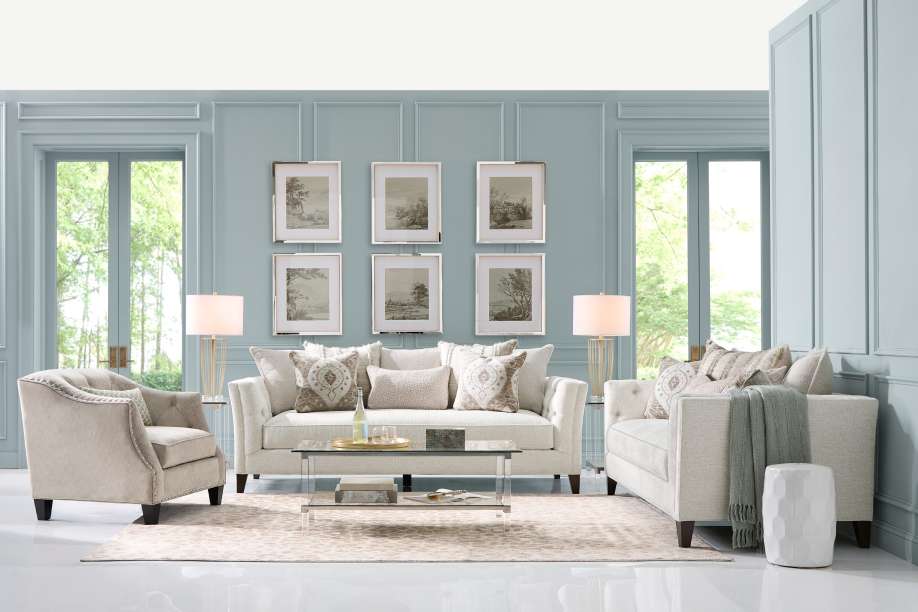 Living room with light blue walls, white furniture, and framed artwork.
