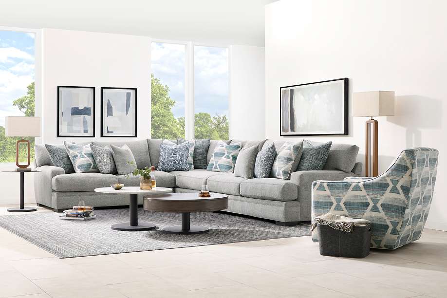 A gray sectional sofa with decorative pillows, a patterned armchair, and a coffee table.
