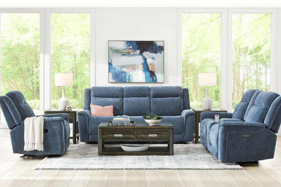 Blue reclining sofa and chairs with a coffee table and artwork.
