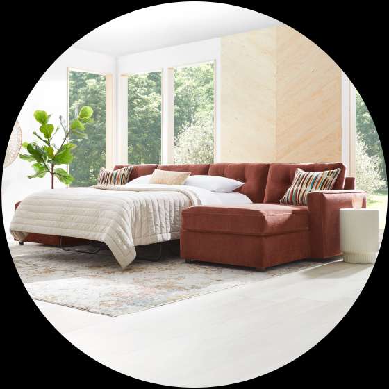 A rust-colored sectional sofa with a pull-out bed in a bright room.
