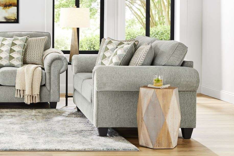 Gray sofa with patterned pillows, a throw blanket, and a wooden side table.
