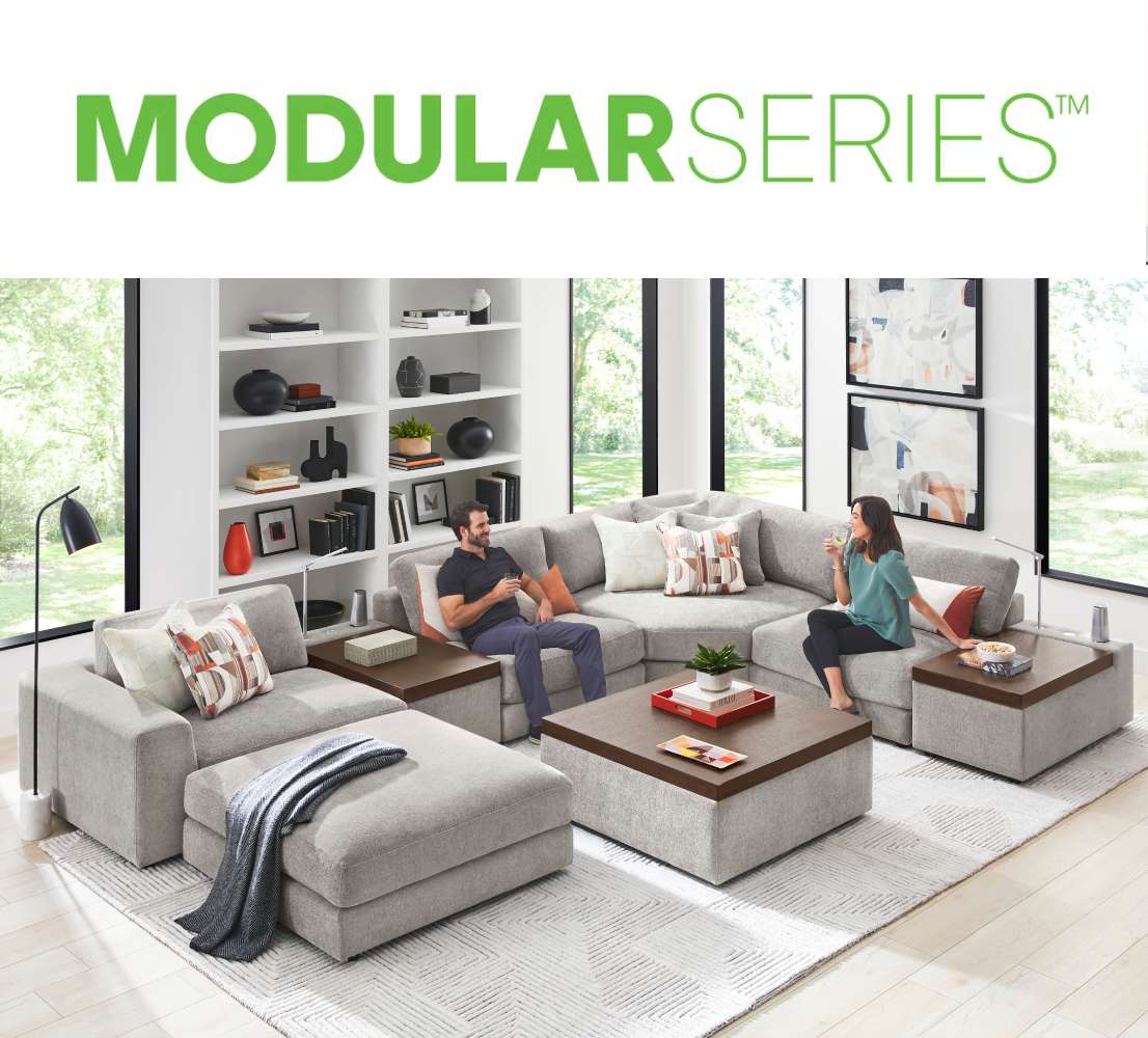 MODULARSERIES™ A modern gray modular sectional sofa with two people sitting on it.
