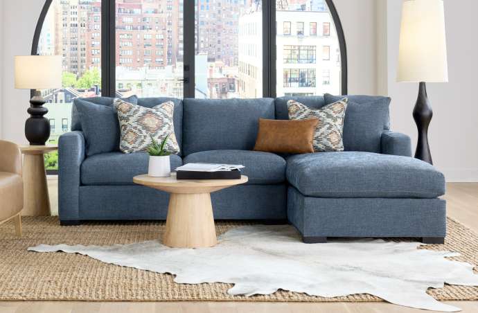 Blue sectional sofa with patterned pillows, a brown leather pillow, and a wooden coffee table.
