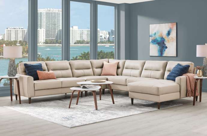 Beige sectional sofa in a living room with a view of a city and water.
