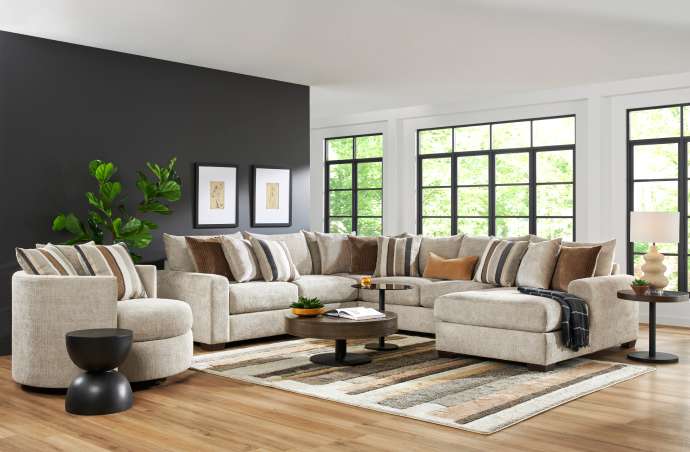 A sectional sofa with accent pillows, a round chair, and a rug.
