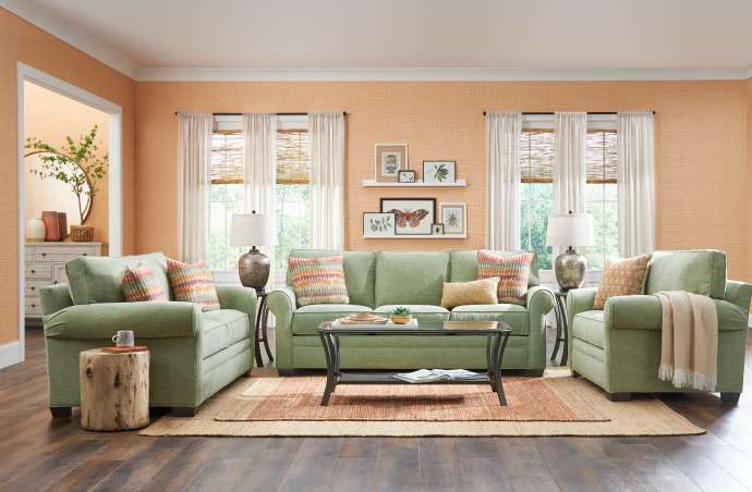 A living room with green furniture, a coffee table, and framed artwork.
