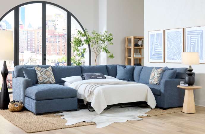 Blue sectional sofa with a pull-out bed in a modern living room.
